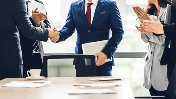 Business professional shaking hands with stakeholders in meeting