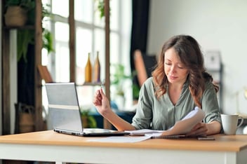 Young woman working from home office. Freelancer using laptop and the Internet. Workplace in living room. 