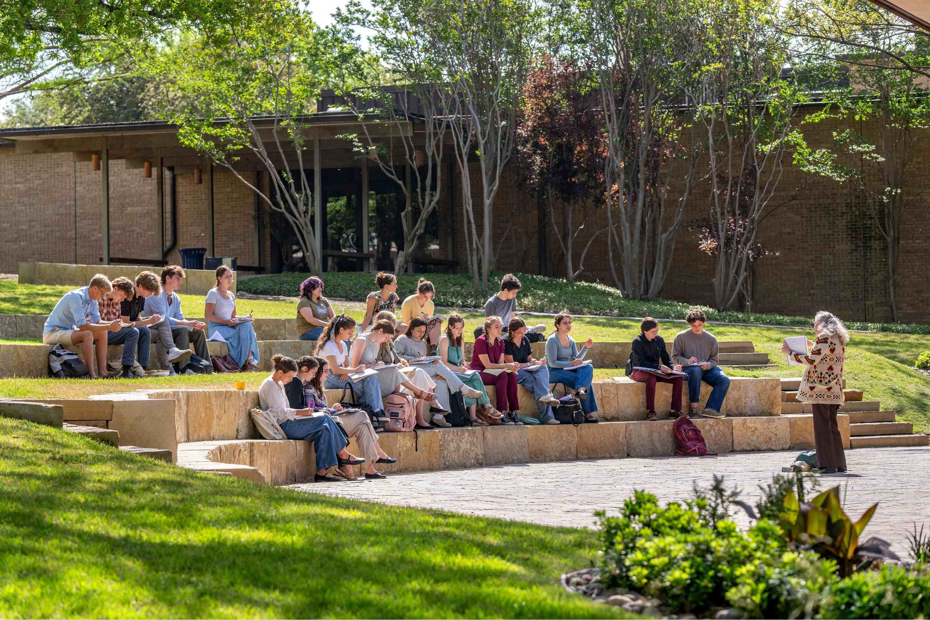 UDallas students sitting on the church lawn